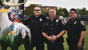 police officers standing next to an elk statue