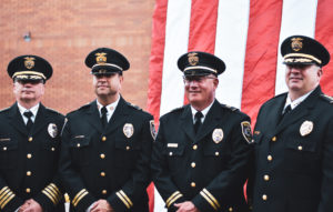 police officers standing in front of an American flag in formal uniform