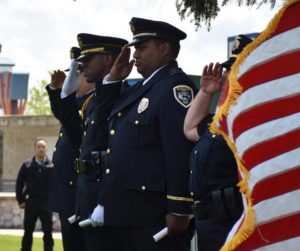 Police officers saluting at a ceremony with the American flag